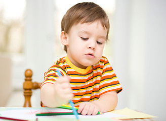 Image showing Little boy is drawing on white paper