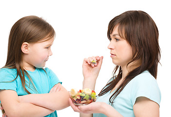 Image showing Mother is trying to feed her daughter