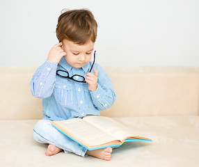 Image showing Little boy is reading book