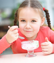 Image showing Little girl is eating ice-cream in parlor