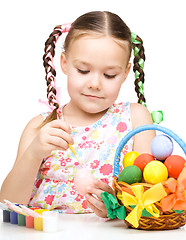 Image showing Little girl is painting eggs preparing for Easter