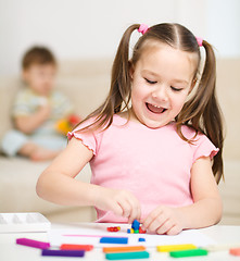 Image showing Little girl is playing with plasticine