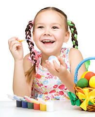 Image showing Little girl is painting eggs preparing for Easter