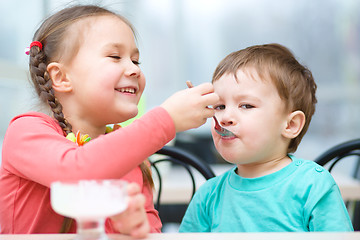 Image showing Girl is feeding his little brother with ice-cream