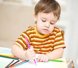 Image showing Little boy is drawing on white paper