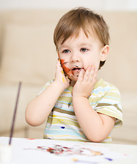 Image showing Little boy is playing with paints