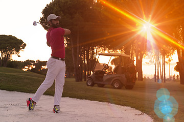 Image showing golfer hitting a sand bunker shot on sunset