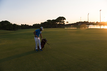 Image showing golfer  walking and carrying golf  bag at beautiful sunset