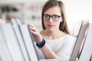 Image showing portrait of famale student selecting book to read in library