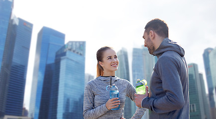 Image showing smiling couple with bottles of water outdoors