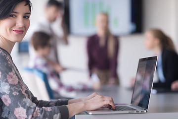 Image showing young business woman at office working on laptop with team on me