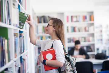 Image showing famale student selecting book to read in library