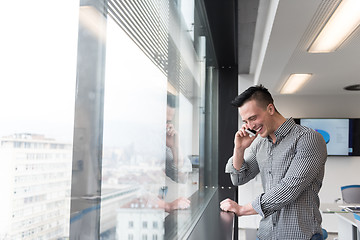 Image showing young business man speaking on  smart phone at office