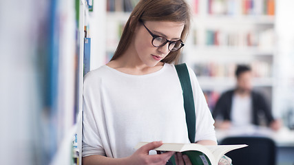 Image showing portrait of famale student reading book in library