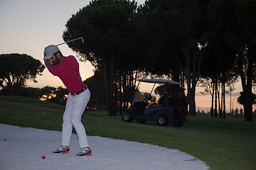 Image showing golfer hitting a sand bunker shot on sunset