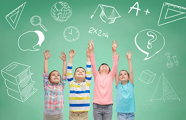 Image showing happy children raising hands over green blackboard