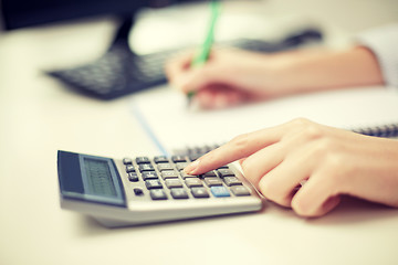 Image showing close up of woman with calculator taking notes