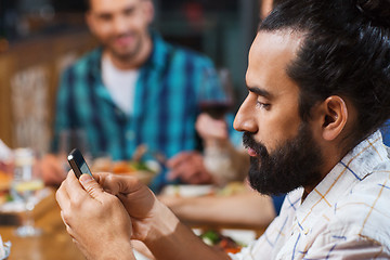 Image showing man with smartphone and friends at restaurant