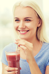 Image showing smiling woman drinking juice or shake at home