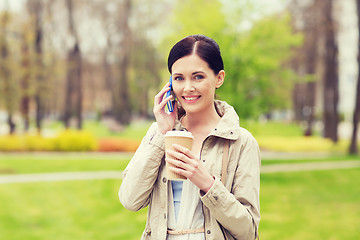 Image showing smiling woman with smartphone and coffee in park