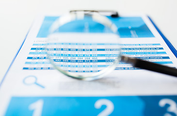 Image showing close up of financial report and magnifying glass