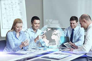 Image showing smiling business people with gadgets in office