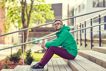 Image showing happy young hipster man sitting on stairs in city