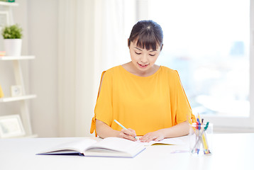 Image showing happy asian young woman student learning at home