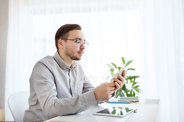 Image showing creative male office worker texting on smarphone