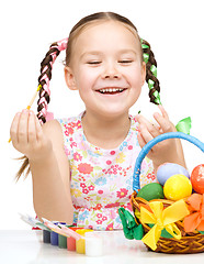 Image showing Little girl is painting eggs preparing for Easter