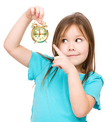 Image showing Little girl is holding small alarm clock