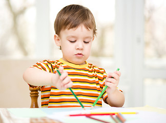 Image showing Little boy is drawing on white paper