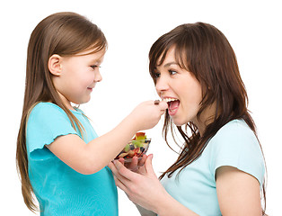 Image showing Daughter is feeding her mother with fruit salad