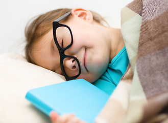 Image showing Girl is sleeping with her book and glasses