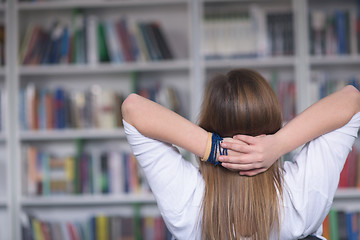 Image showing female student study in library, using tablet and searching for 