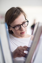 Image showing portrait of famale student selecting book to read in library