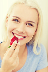 Image showing happy woman eating strawberry at home