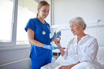 Image showing nurse giving medicine to senior woman at hospital