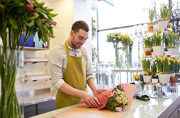 Image showing florist wrapping flowers in paper at flower shop