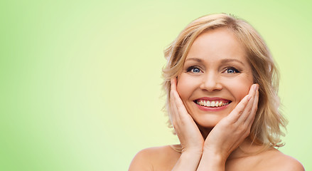 Image showing smiling woman with bare shoulders touching face