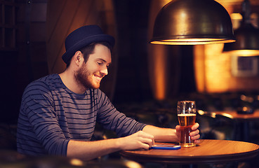 Image showing man with smartphone and beer texting at bar