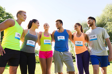 Image showing happy friends or couple with racing badge numbers