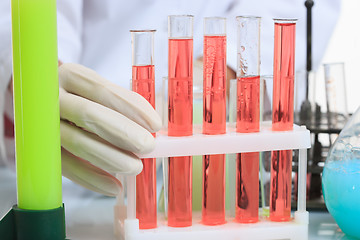 Image showing hands holding test tubes with chemical elements. 