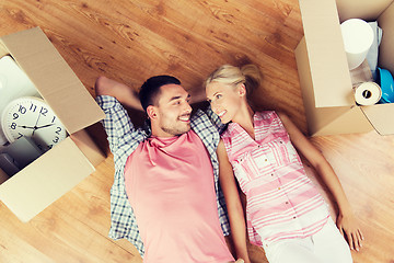 Image showing happy couple lying on floor among cardboard boxes