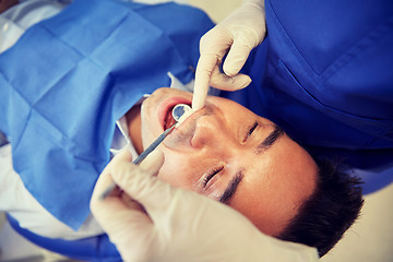 Image showing close up of dentist checking male patient teeth