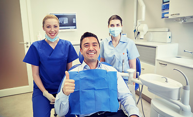 Image showing happy female dentists with man patient at clinic