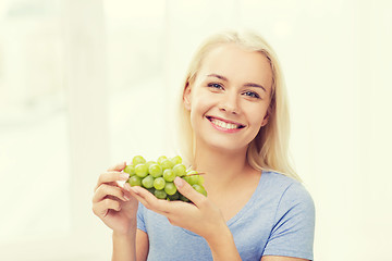 Image showing happy woman eating grapes at home