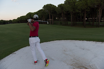 Image showing golfer hitting a sand bunker shot on sunset