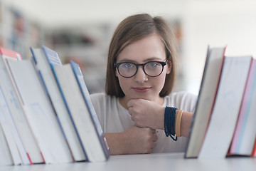 Image showing portrait of famale student selecting book to read in library