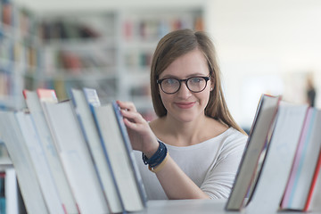 Image showing portrait of famale student selecting book to read in library